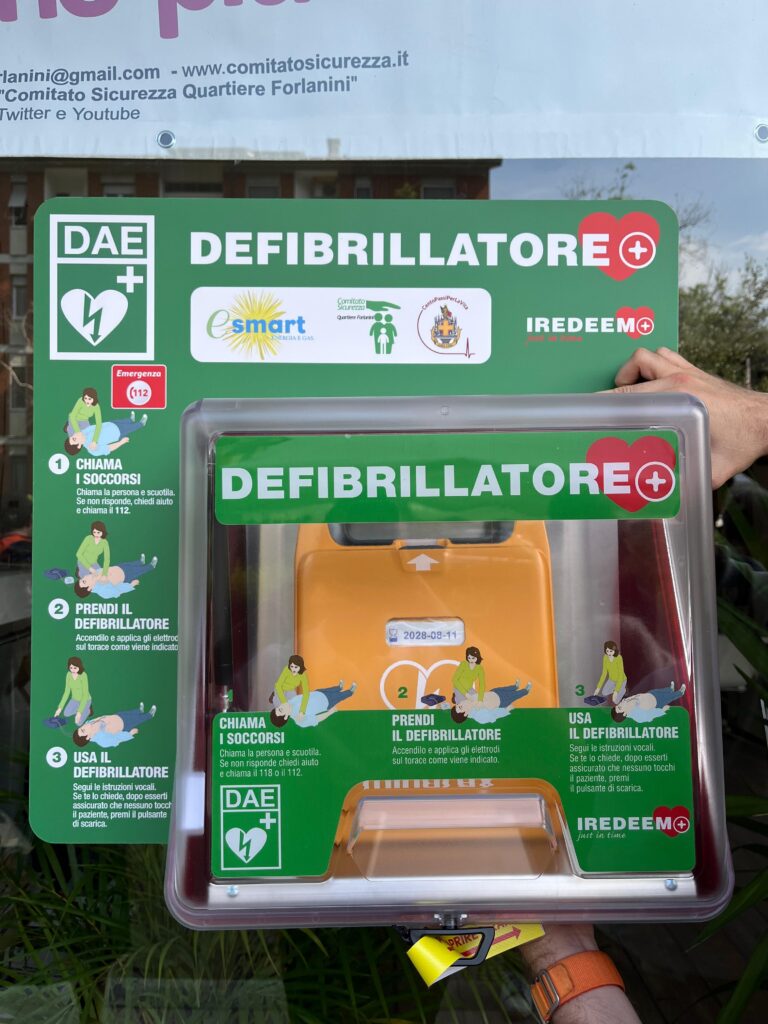 Dettaglio ravvicinato della teca verde contenente un defibrillatore automatico esterno (DAE) installato in un luogo pubblico per il progetto CentoPassiPerLaVita.