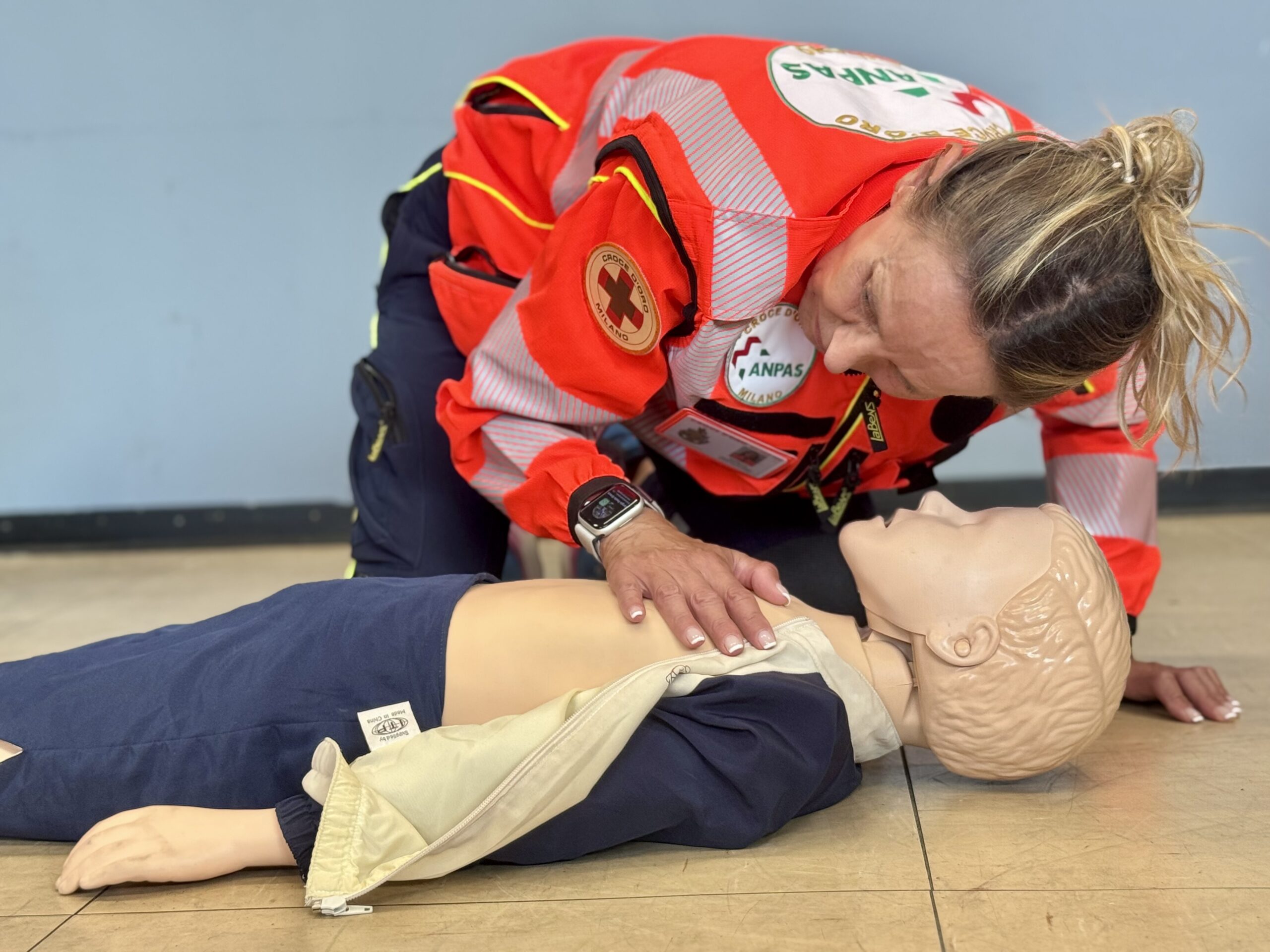 Soccorritrice della Croce d'Oro Milano durante una simulazione pratico-didattica di rianimazione cardiopolmonare pediatrica su un manichino neonatale.